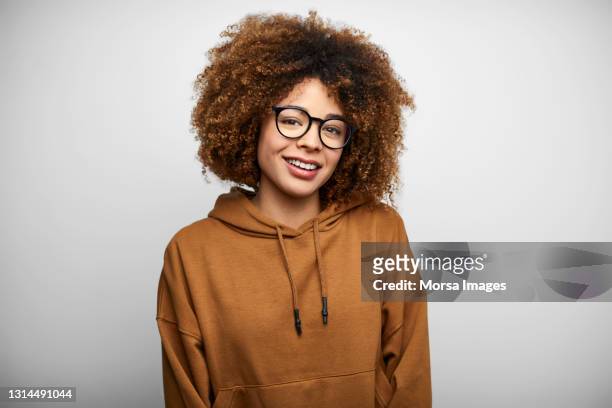 smiling young woman against white background - black jacket photos et images de collection