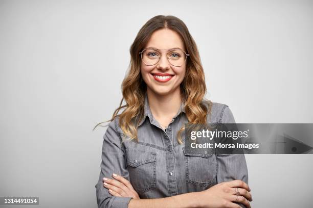 beautiful woman with arms crossed against white background - brillen stock-fotos und bilder