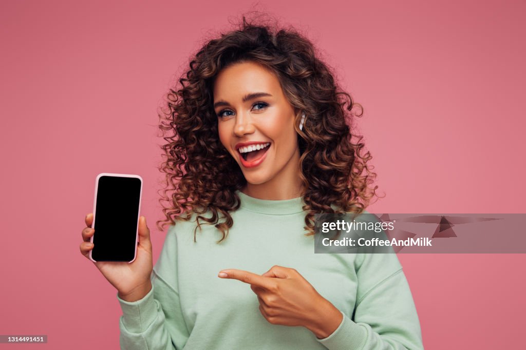 Hermosa chica emocional sosteniendo teléfono inteligente