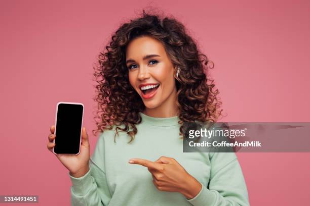 hermosa chica emocional sosteniendo teléfono inteligente - demonstration fotografías e imágenes de stock