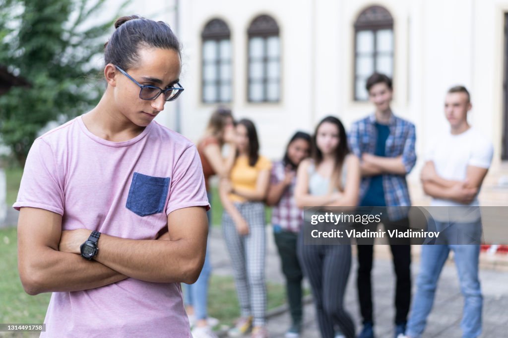 Trauriger männlicher Schüler von seinen Klassenkameraden gebullt