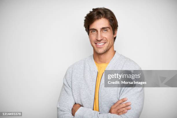 confident male in casuals against white background - yellow coat stock-fotos und bilder