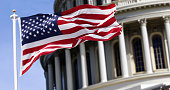 The flag of the united states of america flying in front of the capitol building blurred in the background