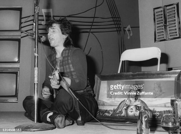 American singer-songwriter and guitarist Johnny Thunders , wearing a tartan waistcoat, sitting cross-legged as he plays an impromptu set at the...