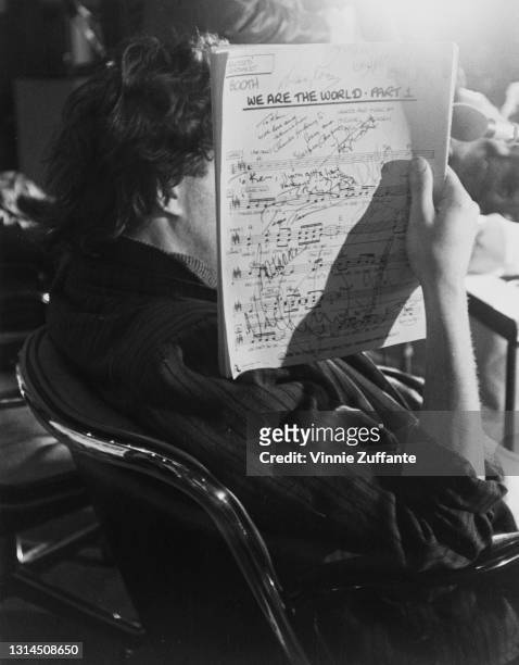 Irish singer-songwriter Bob Geldof obscured by the autographed sheet music for the charity single 'We Are the World' at A&M Recording Studios in Los...