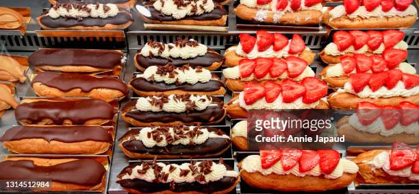 éclairs in many flavours lined up on shop display - cake display stock-fotos und bilder