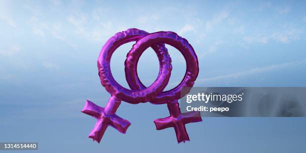 青い空に浮かぶピンクの女性の性別シンボルの形をした箔風船のペア - female symbol ストックフォトと画像