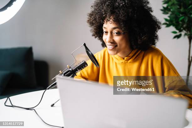 young woman podcasting while looking at laptop at home - filming stock pictures, royalty-free photos & images