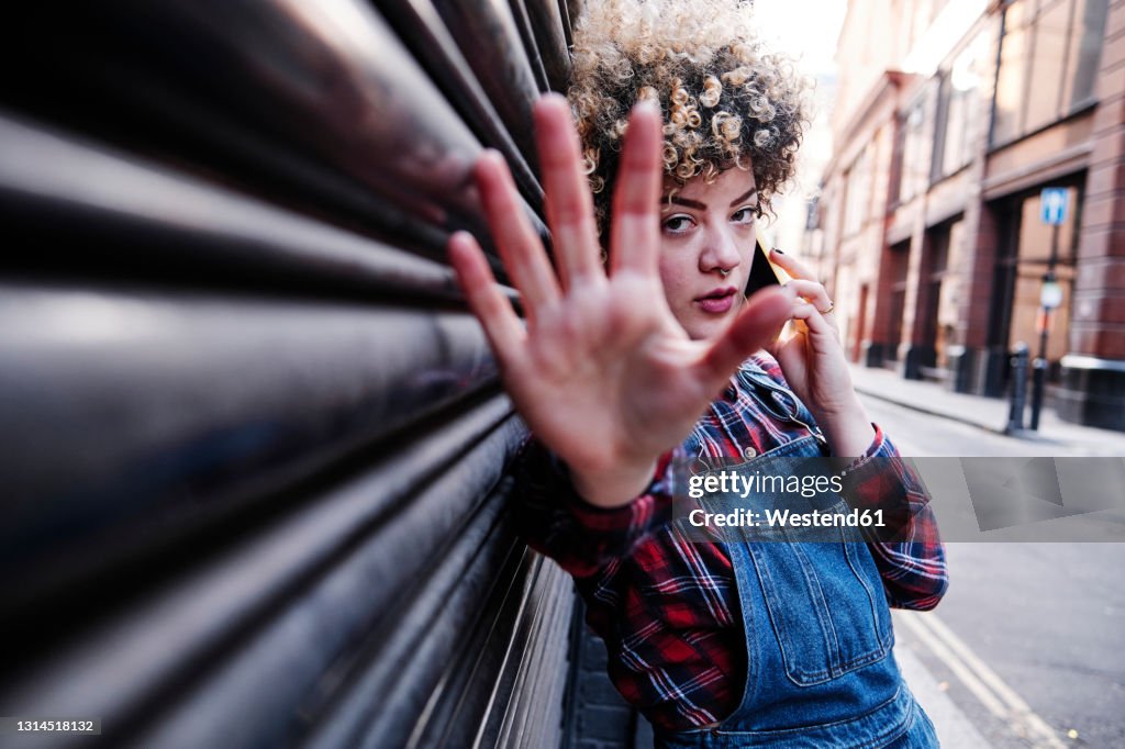 Woman showing stop gesture while talking on mobile phone