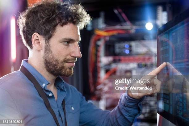 male it professional touching computer screen in data center - digital workplace stock-fotos und bilder