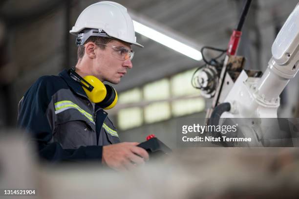 welding engineer using remote controller to operate robotic arm welding torch in chassis part production line. - remote controlled fotografías e imágenes de stock
