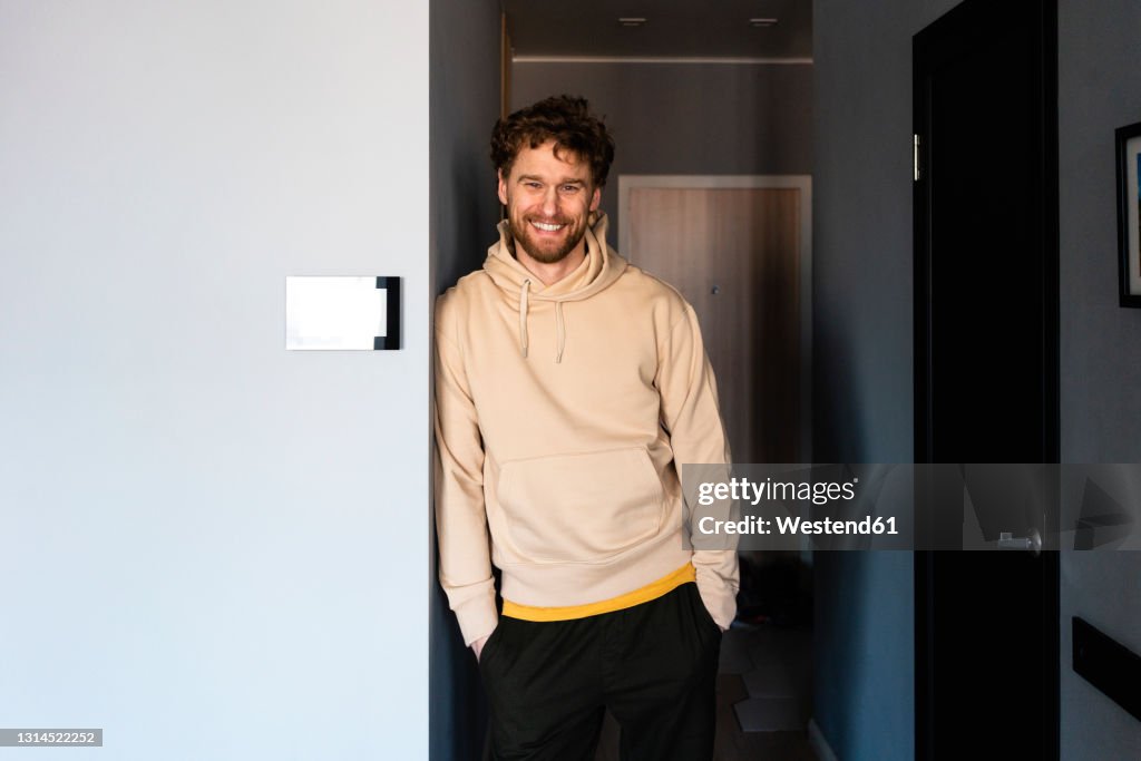 Smiling man standing with hands in pockets at home