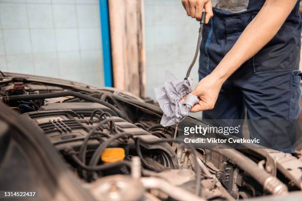 il meccanico sta controllando l'olio motore in macchina. - marcare foto e immagini stock