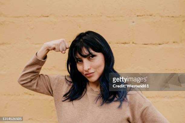 beautiful woman flexing muscles in front of wall - flexing muscles ストックフォトと画像
