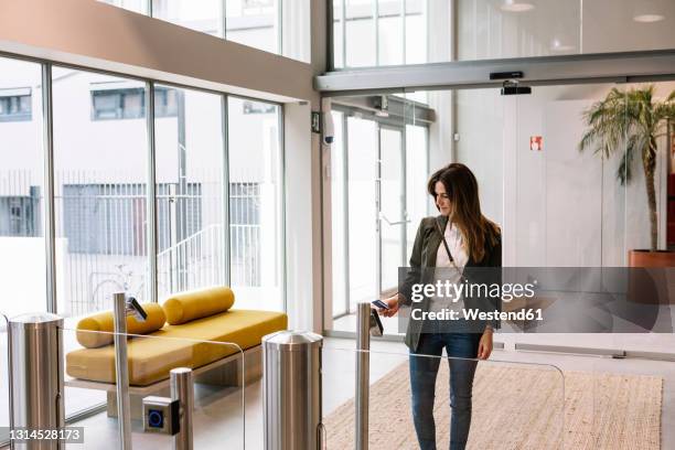 mid adult woman showing id card at reader while entering office - torniquete imagens e fotografias de stock