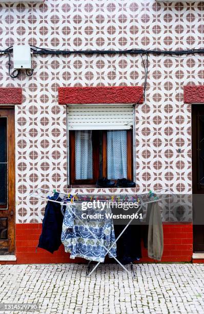 laundry drying on drying rack standing in front of mosaic wall with square tiles - portugal tiles stock pictures, royalty-free photos & images