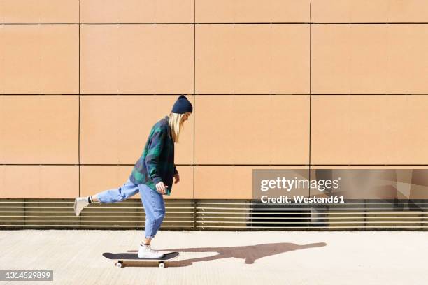 young woman skateboarding during sunny day - women skateboarding stock pictures, royalty-free photos & images