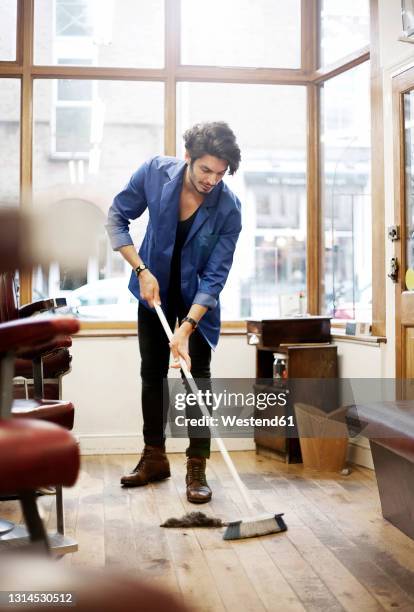 barber sweeping floor in barber shop - busy barber shop stock pictures, royalty-free photos & images