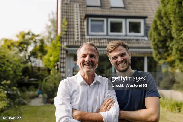 cheerful father and son standing in backyard - erwachsene kinder stock-fotos und bilder