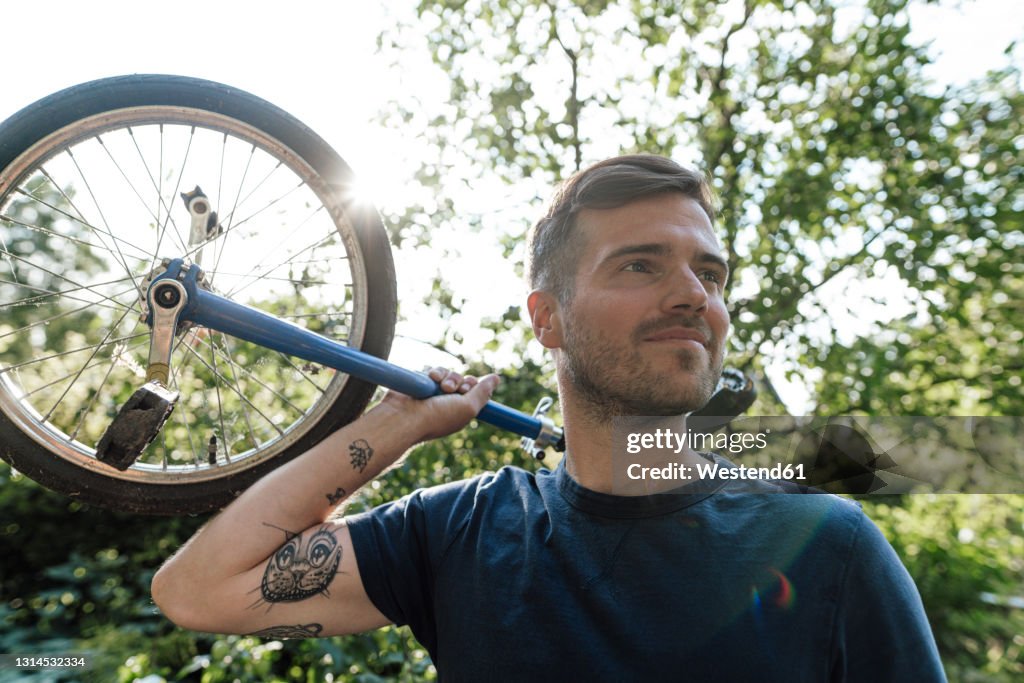 Man with unicycle looking away during sunny day