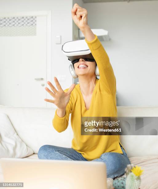 excited woman gesturing while wearing virtual reality headset at home - casques réalité virtuelle photos et images de collection