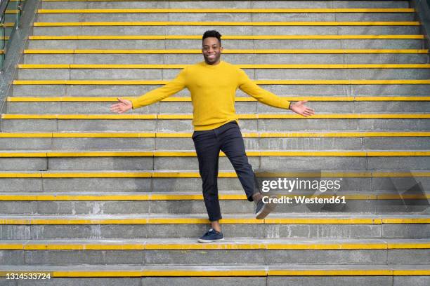 smiling man with arms outstretched standing on staircase - man outstretched arms ストックフォトと画像