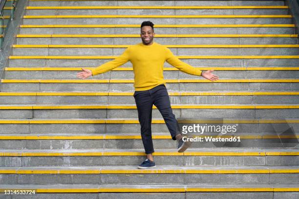 smiling man with arms outstretched standing on staircase - human limb stock pictures, royalty-free photos & images