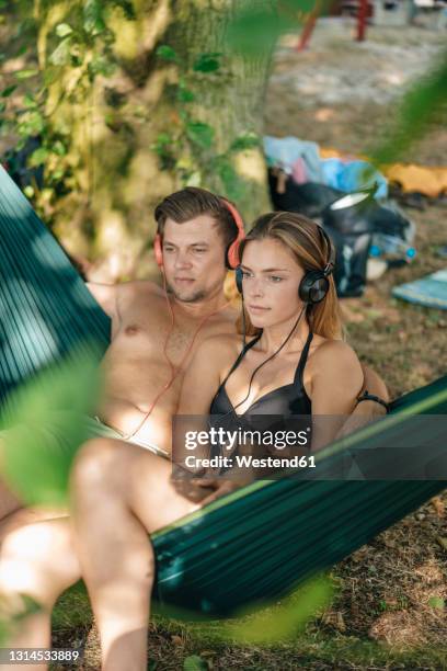 couple relaxing in hammock by the lake, listening music - young man listening music and relaxing in hammock stock pictures, royalty-free photos & images