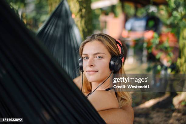 young woman listening music with headphones in a hammock by the lake - young man listening music and relaxing in hammock stock pictures, royalty-free photos & images