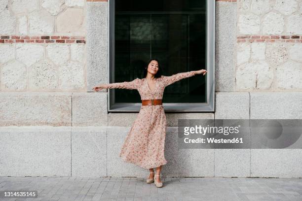 woman with arms outstretched standing by window - 腕を広げる ストックフォトと画像