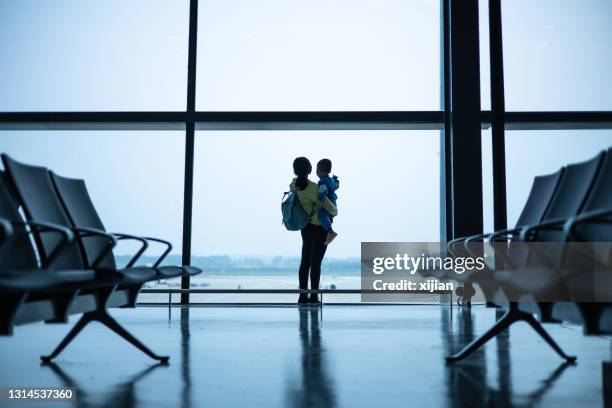 mutter mit sohn schaut aus flughafenfenster - kid in airport stock-fotos und bilder