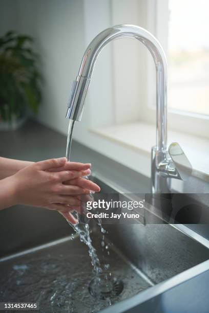 shot of an unrecognisable woman washing her hands in the kitchen sink at home - kitchen sink water stock pictures, royalty-free photos & images