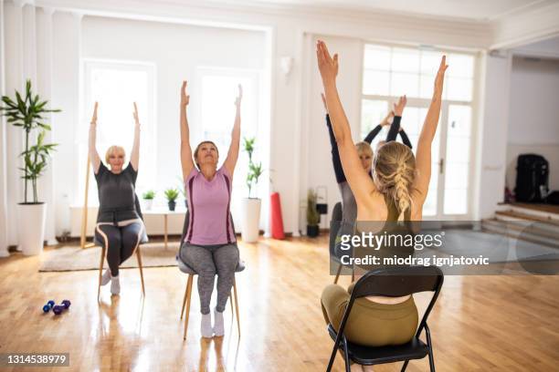 istruttore di yoga femminile che ha lezione di yoga con persone senior su sedie - sedia foto e immagini stock