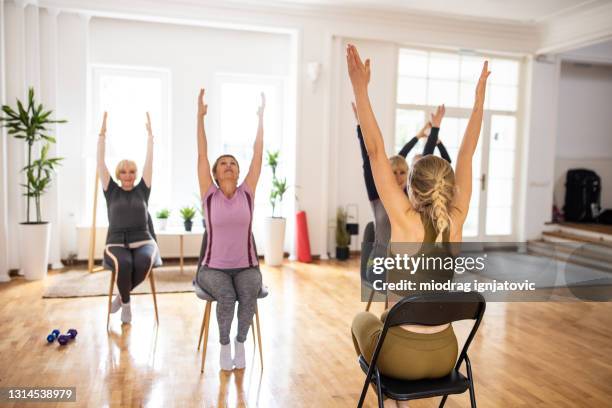 vrouwelijke yogainstructeur die yogaklasse met hogere mensen op stoelen heeft - stoel stockfoto's en -beelden