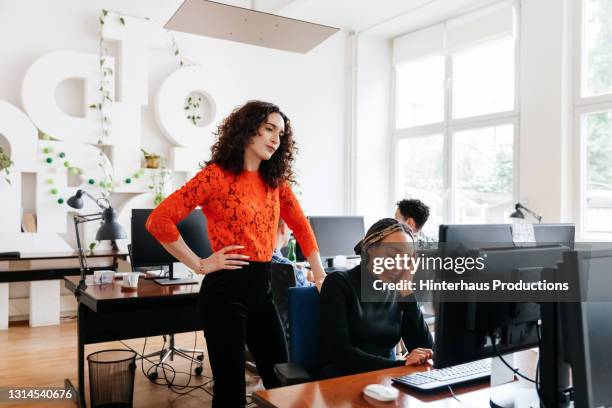 transgender business manager overlooking colleague working - bad employee stock pictures, royalty-free photos & images