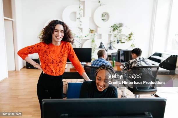 transgender office manager smiling while chatting to colleague - leanincollection man stock pictures, royalty-free photos & images