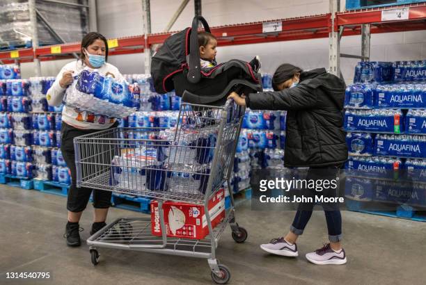 Honduran immigrant Nani helps her aunt Saiyda Gonzalez shop at Sam's Club as her baby cousin looks on a day after the girl arrived to live with...
