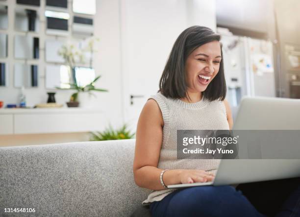shot of a young woman relaxing on her couch using her laptop at home - excitement laptop stock pictures, royalty-free photos & images