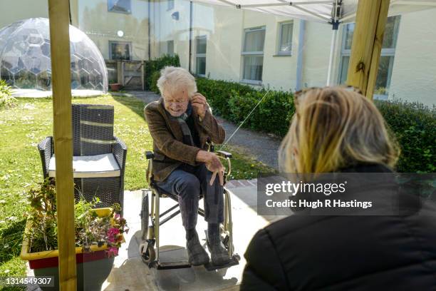 Karen Hastings visits her stepfather Gordon , who suffers from dementia, under a temporary open-air shelter with a clear screen between them, at the...