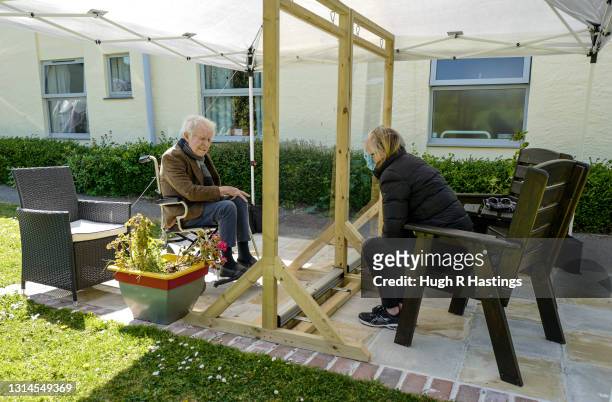 Karen Hastings visits her stepfather Gordon , who suffers from dementia, under a temporary open-air shelter with a clear screen between them, at the...
