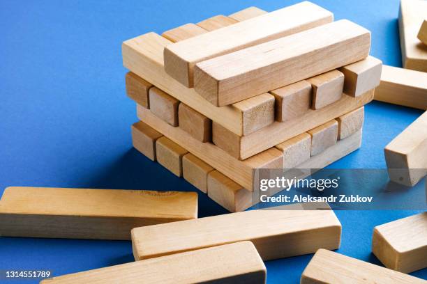 a pile of scattered wooden blocks on a blue background. construction game. build an unfinished and destroyed tower. - jenga stockfoto's en -beelden