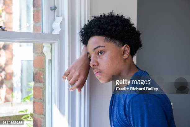 bored teenage boy looking out of a window - teenage boy looking out window stock pictures, royalty-free photos & images