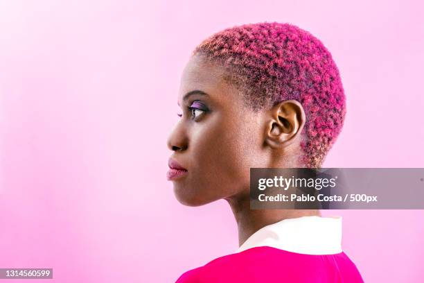 portrait of young woman with pink hair and clothing against pink background,buenos aires,argentina - african woman hair stock-fotos und bilder