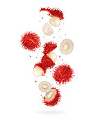 Whole and crushed rambutan fruits in the air, isolated on a white background