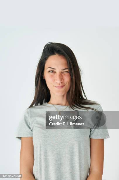 portrait of winking woman on white background - casual young woman on white background stockfoto's en -beelden