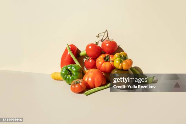 red,green tomatoes, carrots and green beans on the beige background - arm made of vegetables stockfoto's en -beelden