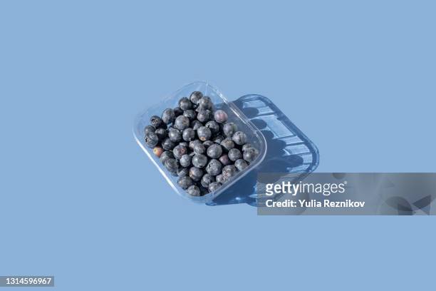 blueberries  in plastic package on the blue background - blueberry stock-fotos und bilder