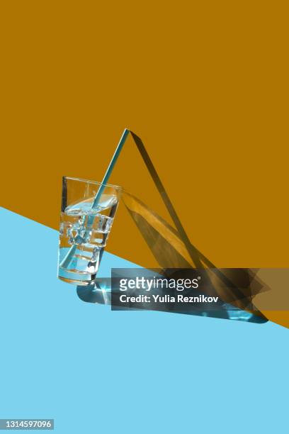 glass of water with ice and straw on the blue-yellow background - straw stock-fotos und bilder