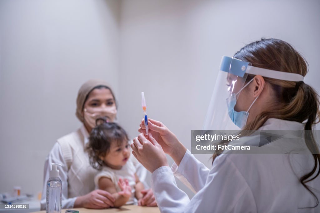 Female doctor preparing medical syringe for a vaccine injection