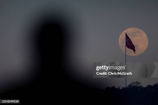 Man watches on as an almost full pink super moon rises over Istanbul on April 26, 2021 in Istanbul, Turkey. The pink super moon is the first of two...